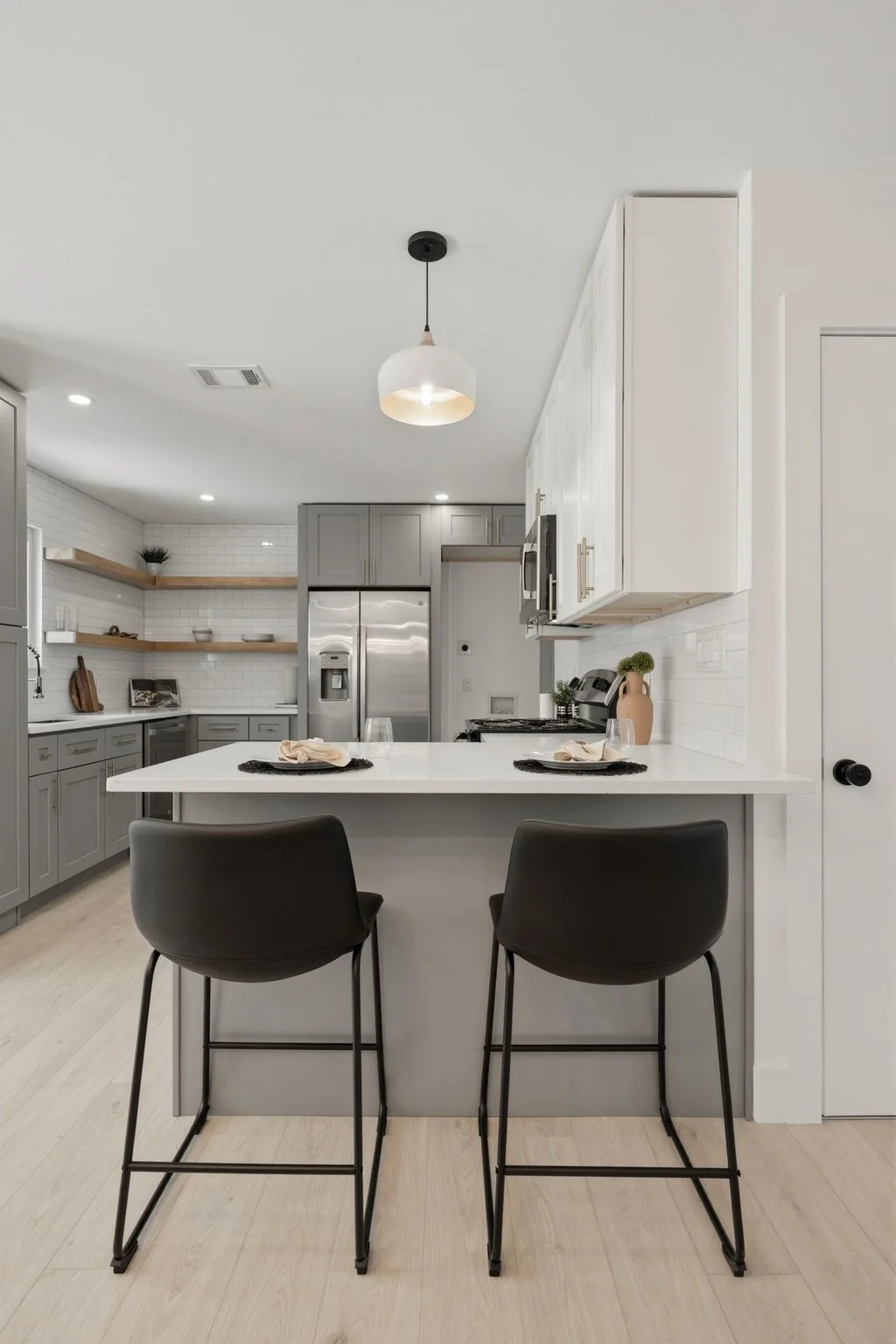 Finished kitchen with gray cabinetry, stone counters, and wood shelving
